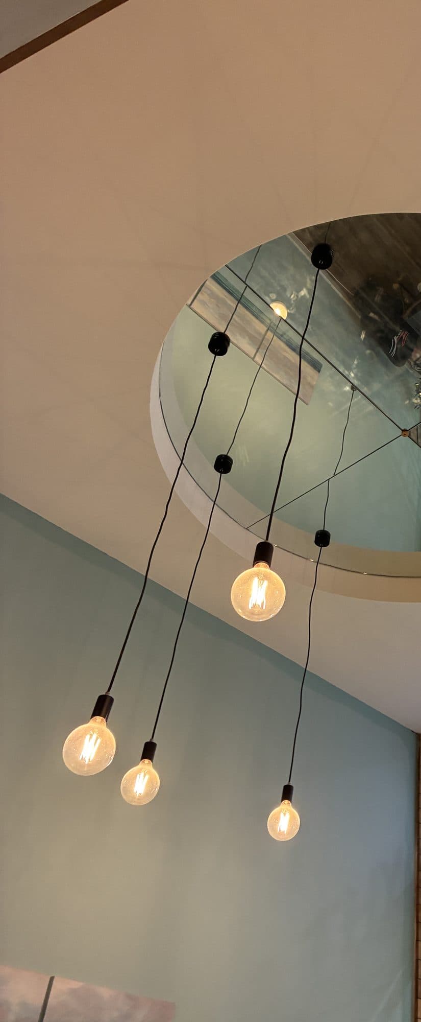 Pendant lights hanging at different heights from a round ceiling opening