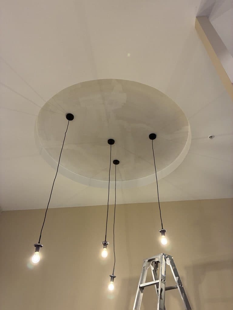 Four pendant lights hung from a round ceiling feature in a back room