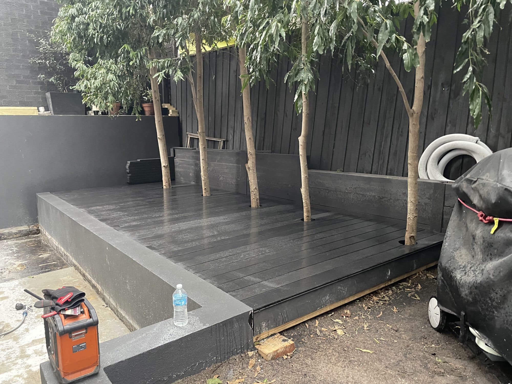 A dark composite deck on a raised rendered edge, with trees behind