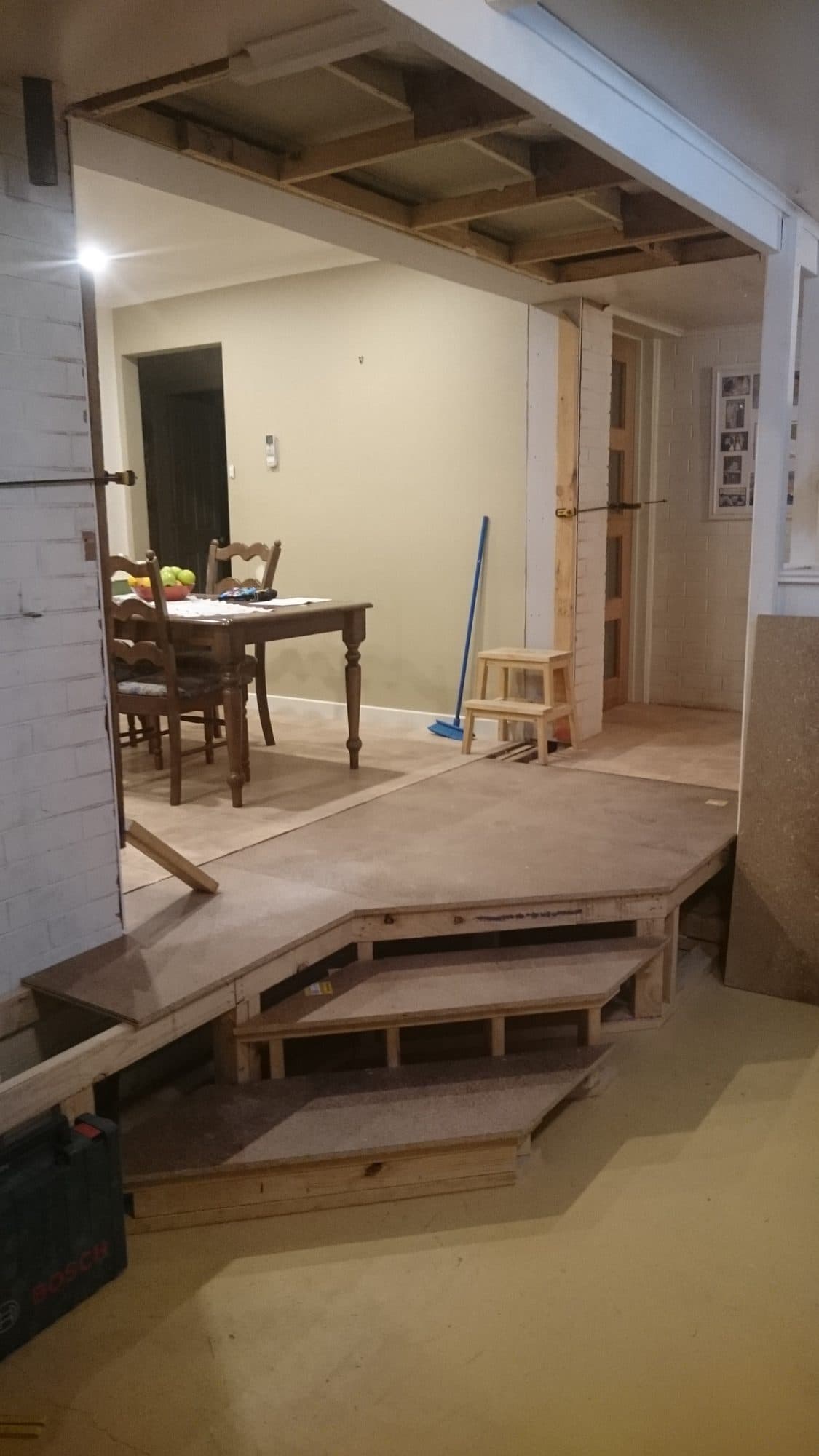 A wall opened up, with new timber steps framed up to the next level