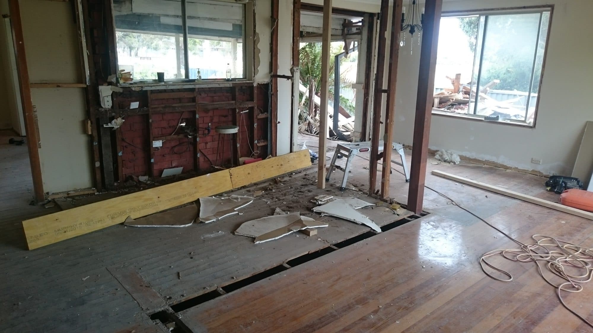 A wall opened up, with a new beam on the floor and exposed brick behind