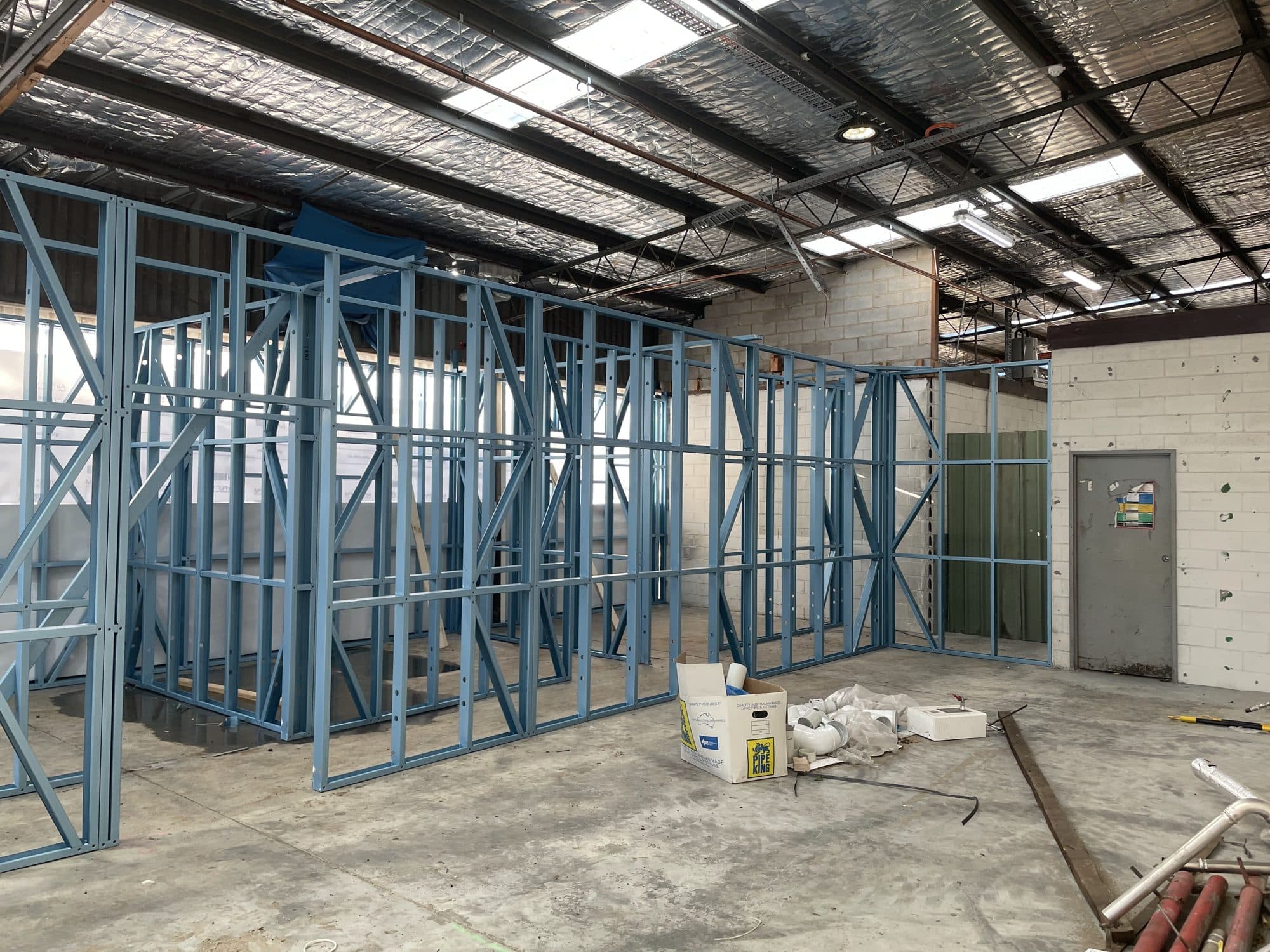 Steel stud partition walls inside a warehouse under a skylit roof
