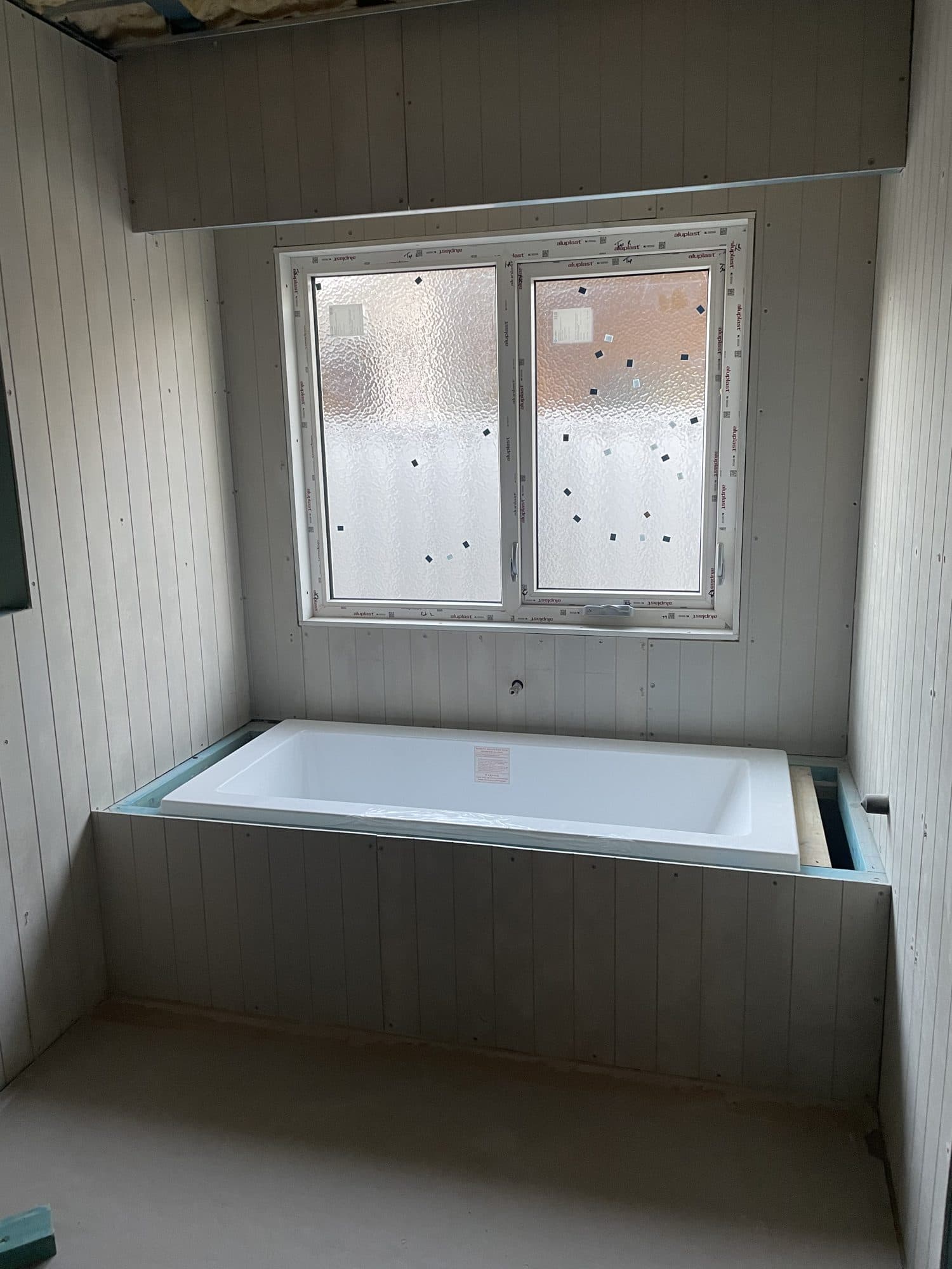 A bathroom lined and ready for painting, with the bath in place under the window