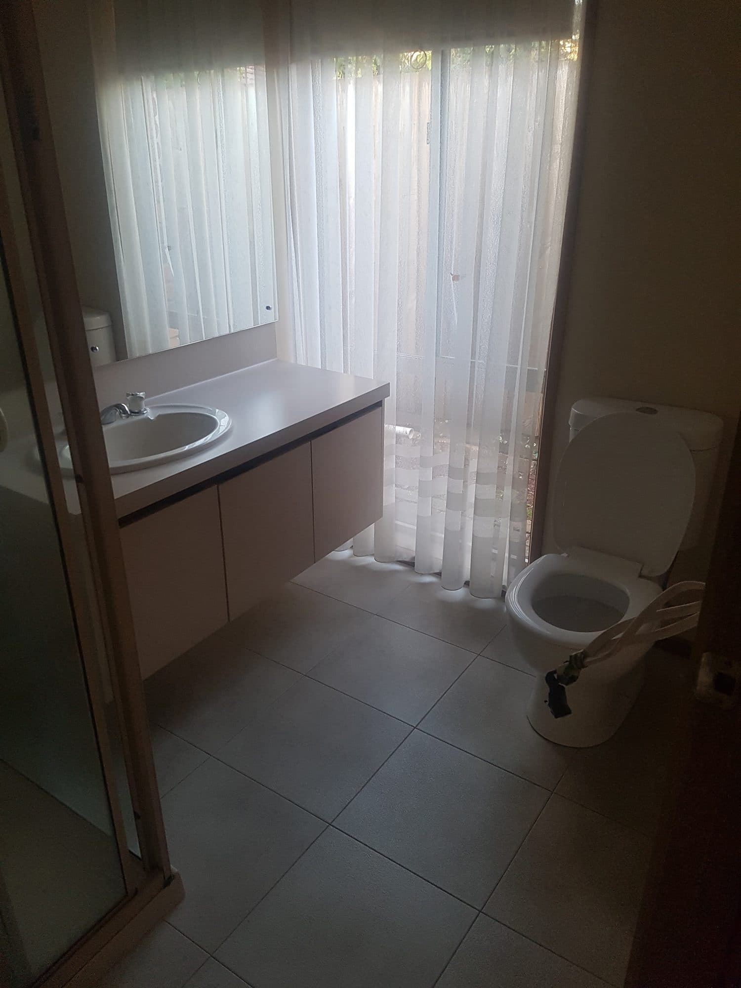 The old ensuite with a vanity and toilet in front of a curtained window