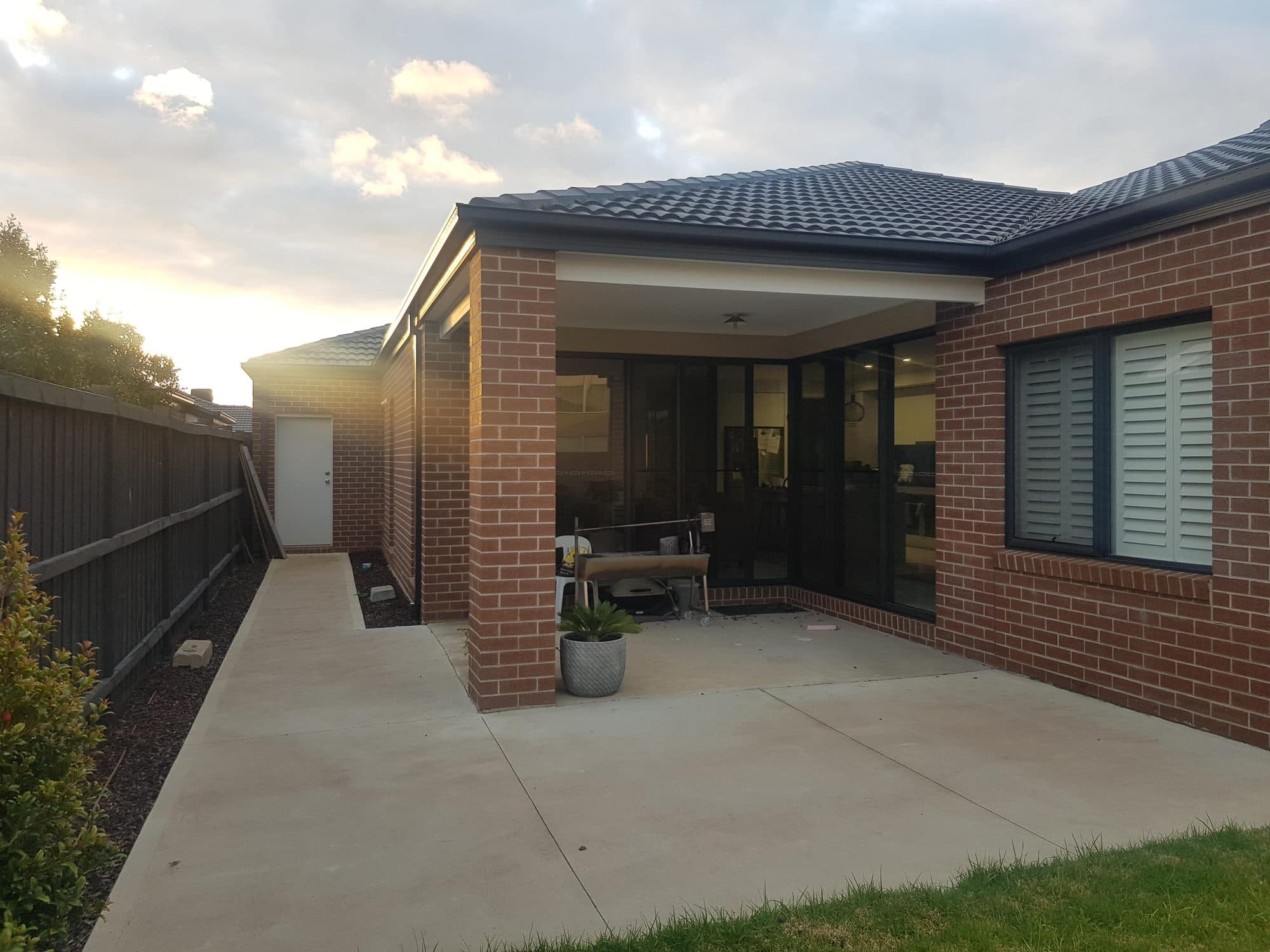A small alfresco at the back of a brick house, with a concrete slab