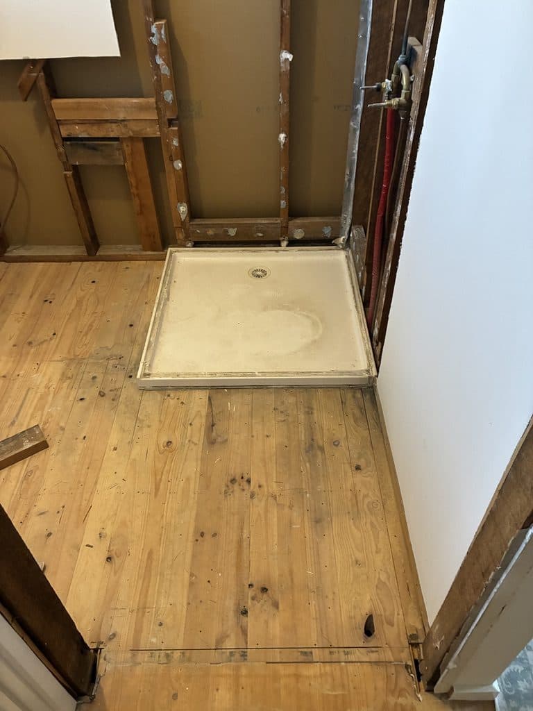 The old shower base sitting on the original timber floor