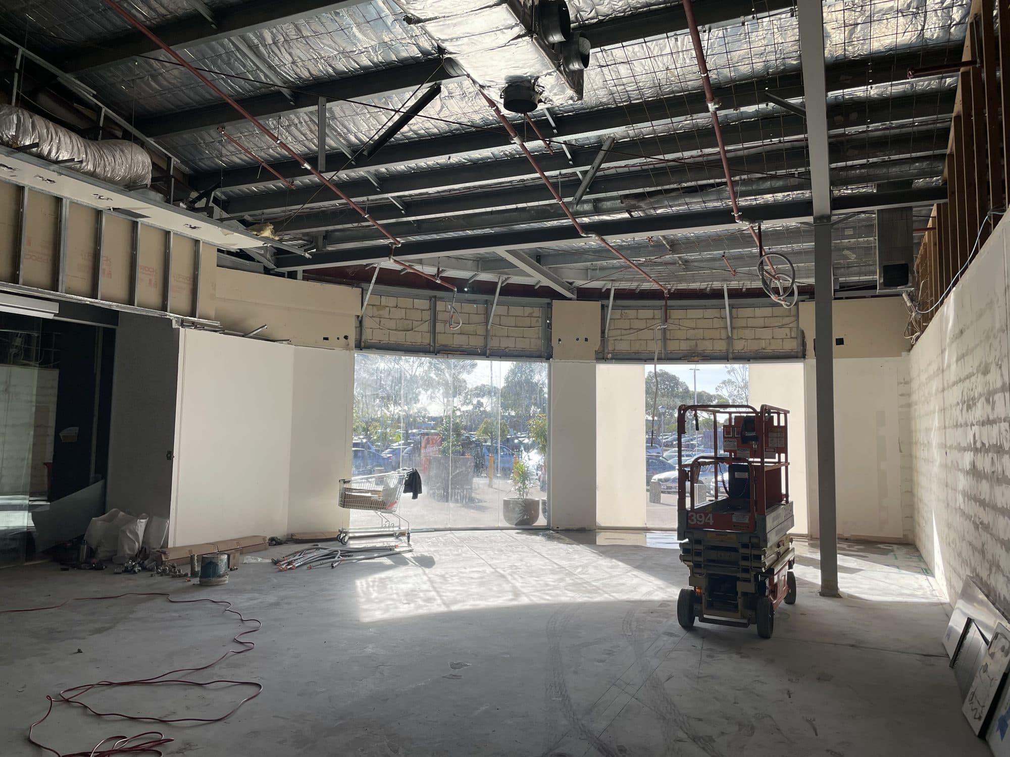 The empty tenancy with exposed roof framing and a scissor lift