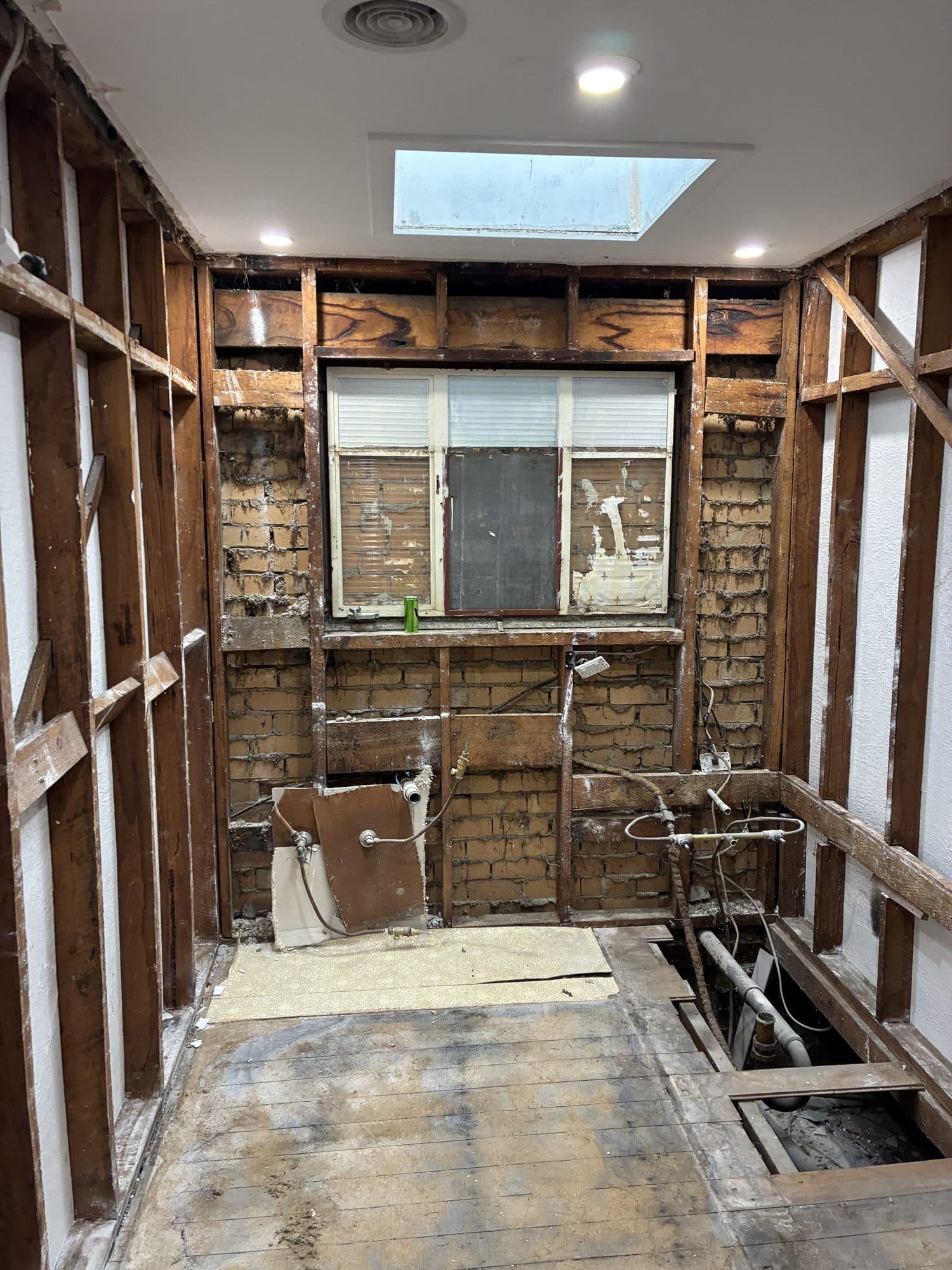 The bathroom stripped to its timber frame, seen from the doorway