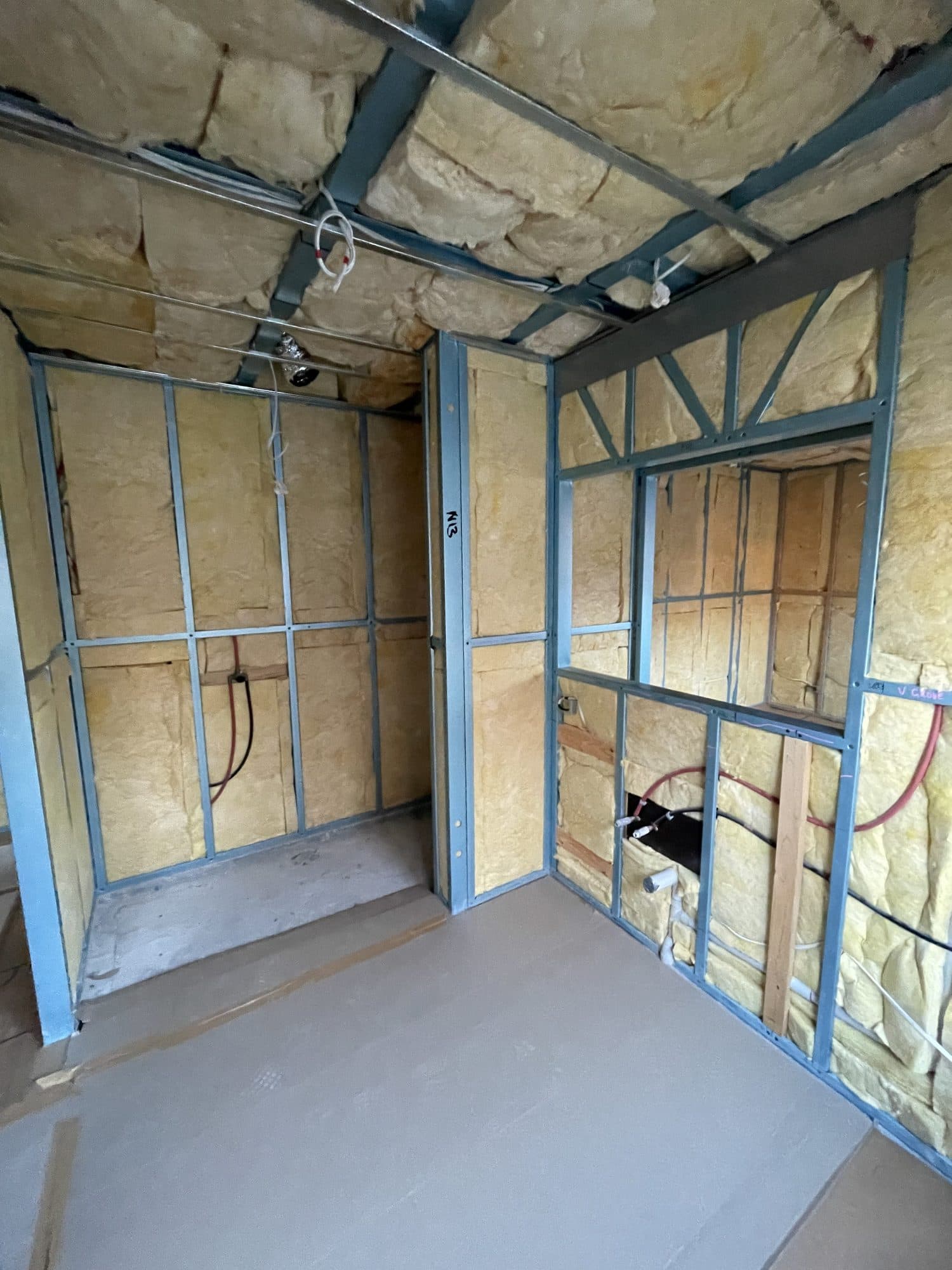 Insulated steel wall frames with the plumbing roughed in
