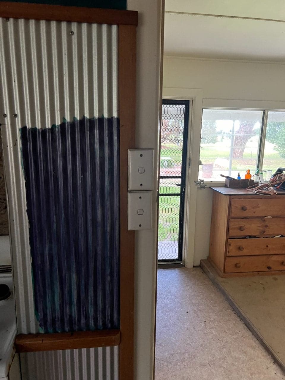 A doorway through to a bedroom, with a corrugated iron wall lining beside it
