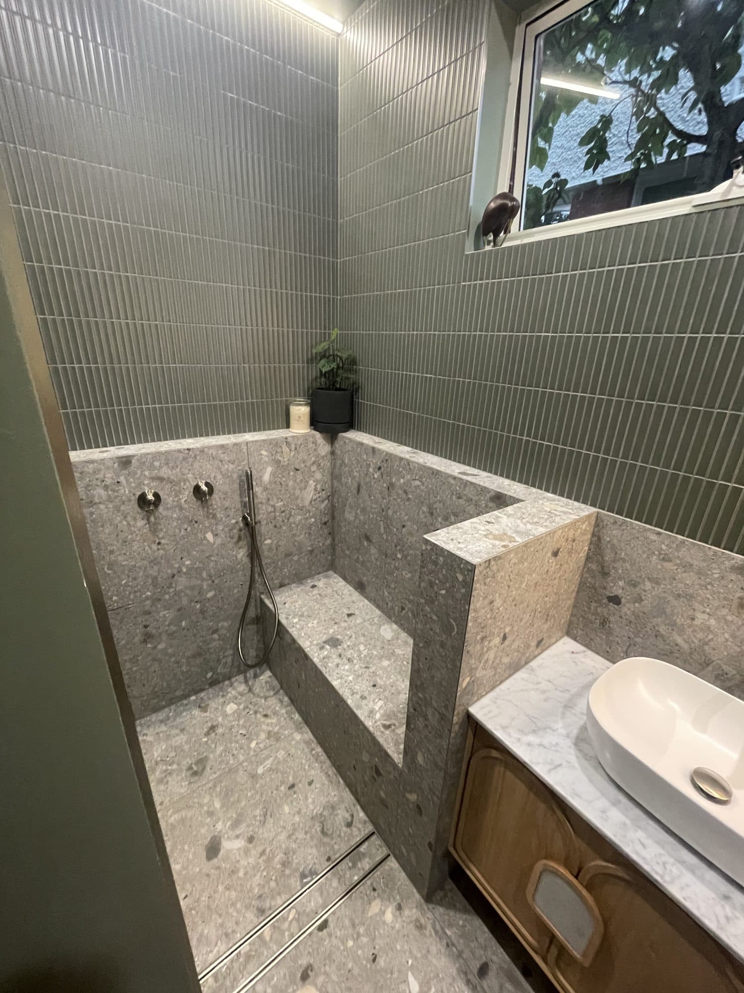 A tiled half wall and step beside the vanity