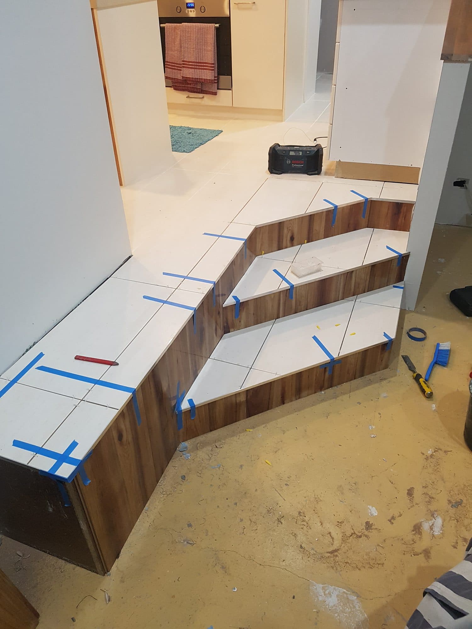 White tile laid on the landing and treads, with timber-look tile on the risers