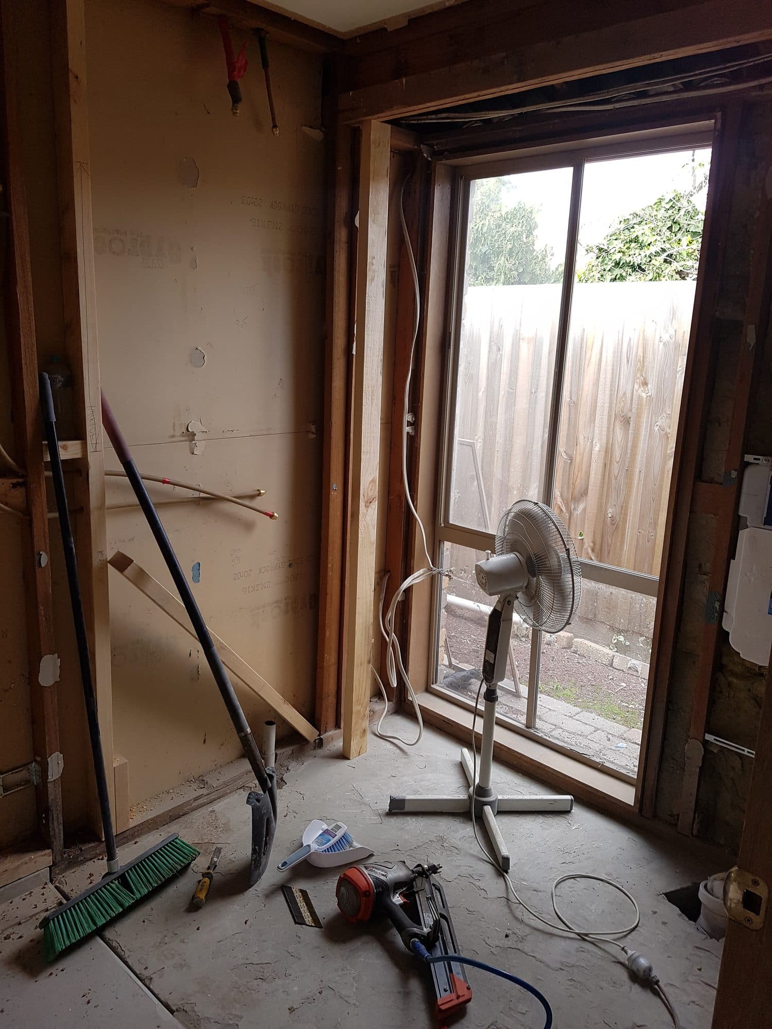 The stripped room with tools on the floor beside the window