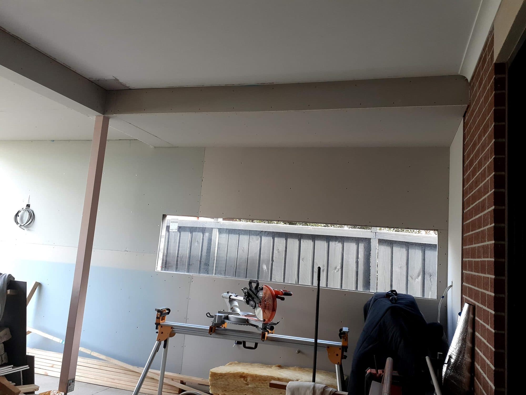 A long opening framed in the new wall, with a saw set up underneath