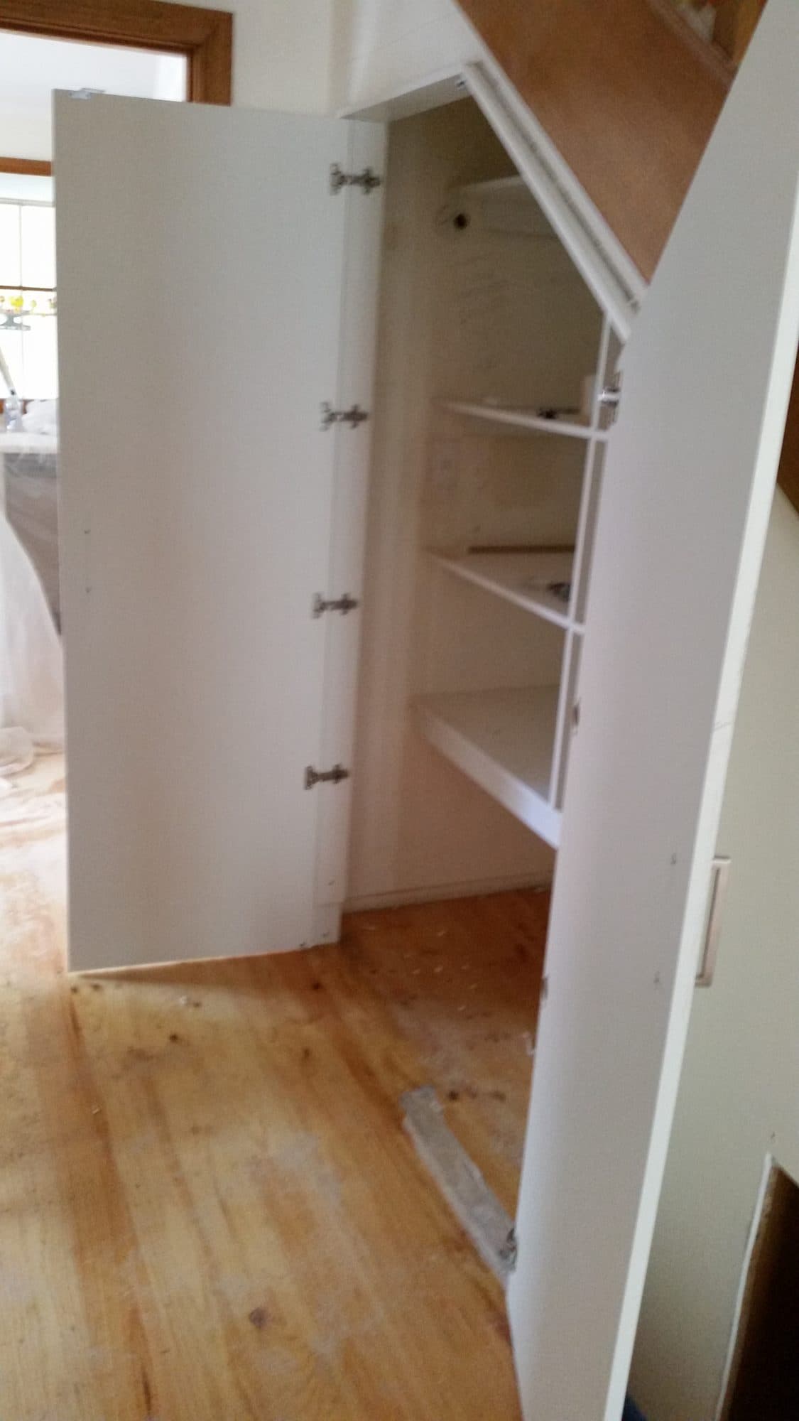 A cupboard door open to shelving inside