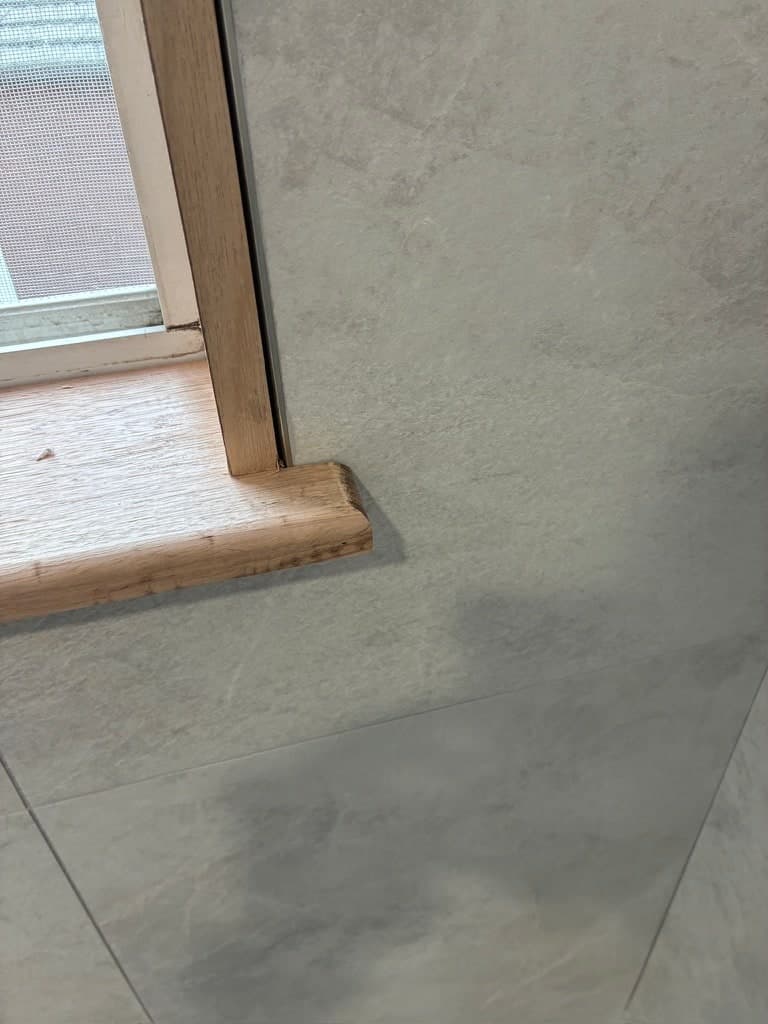 The tiled floor meeting the wall tile under the window reveal