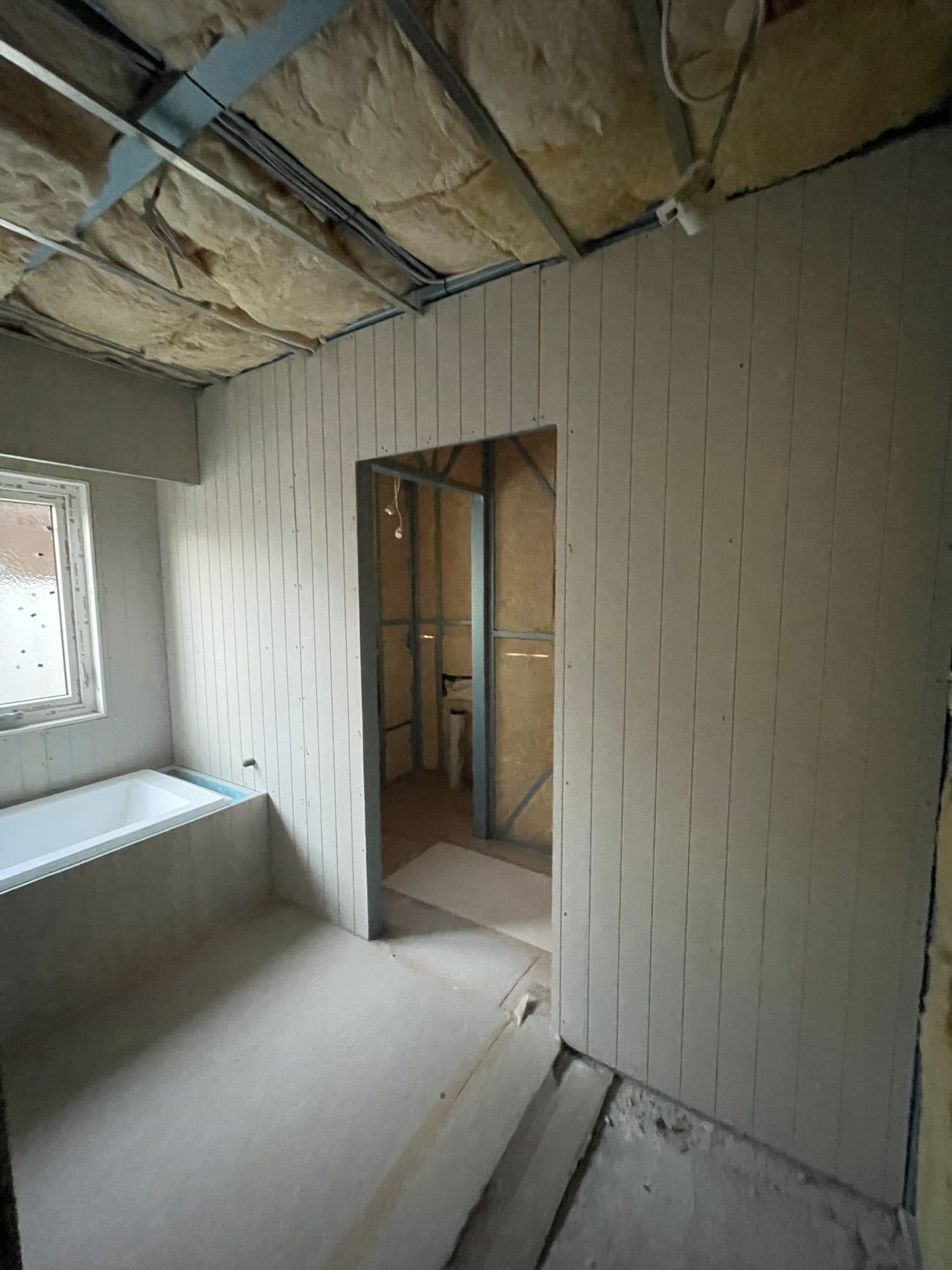 Grooved wall panelling in the bathroom, with the bath beside a doorway