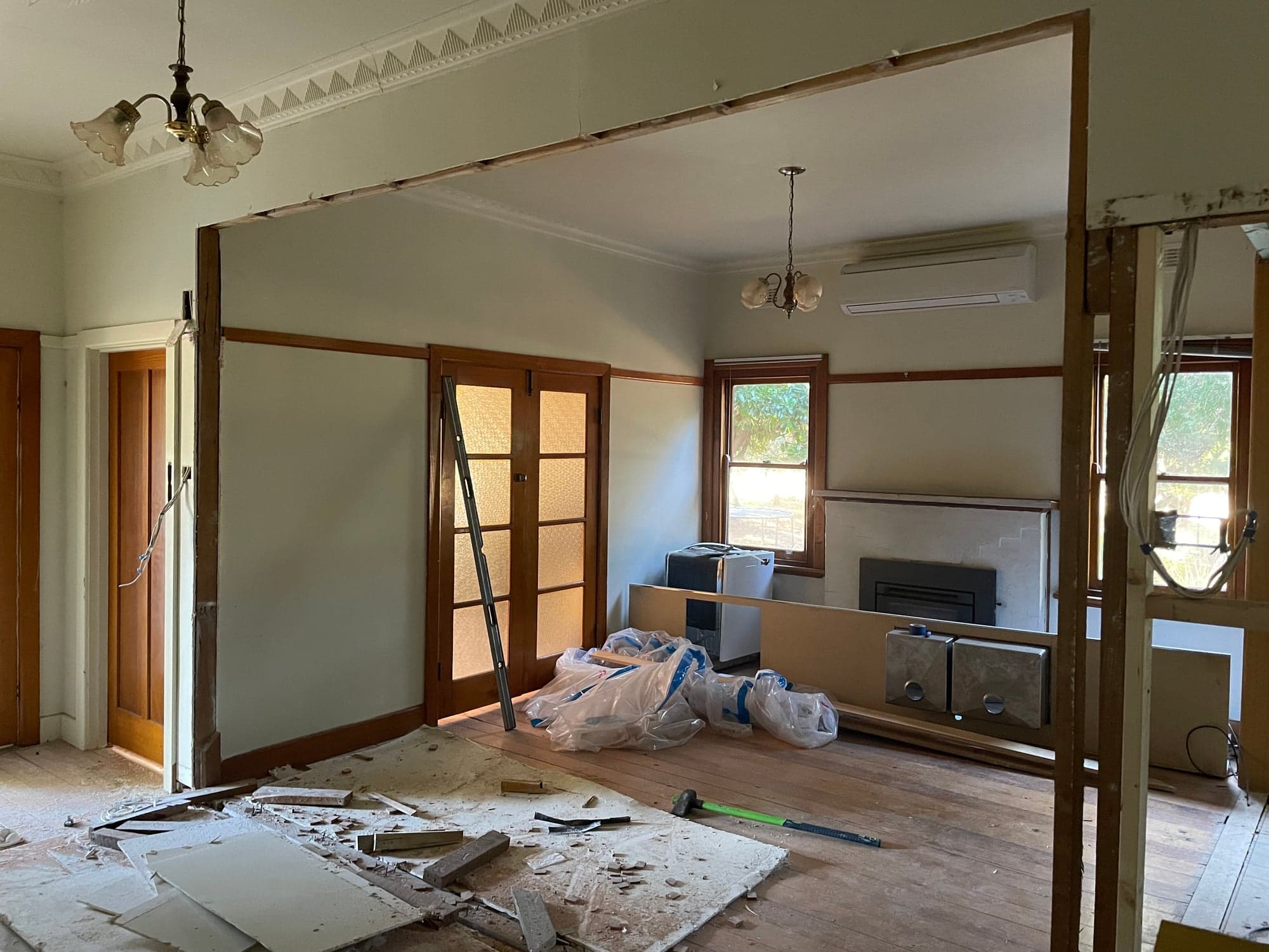 A wide new opening between two rooms, framed in timber, with the fireplace beyond