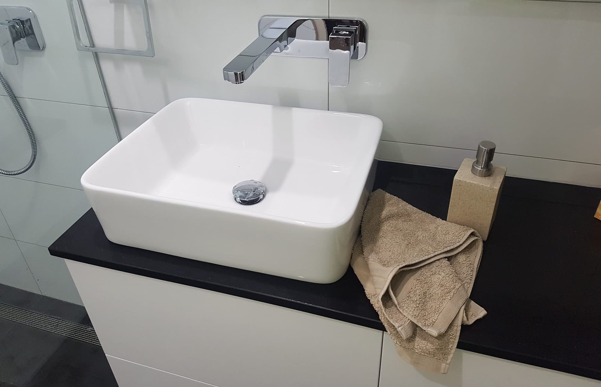 A top-mounted basin on a dark benchtop with a wall-mounted tap