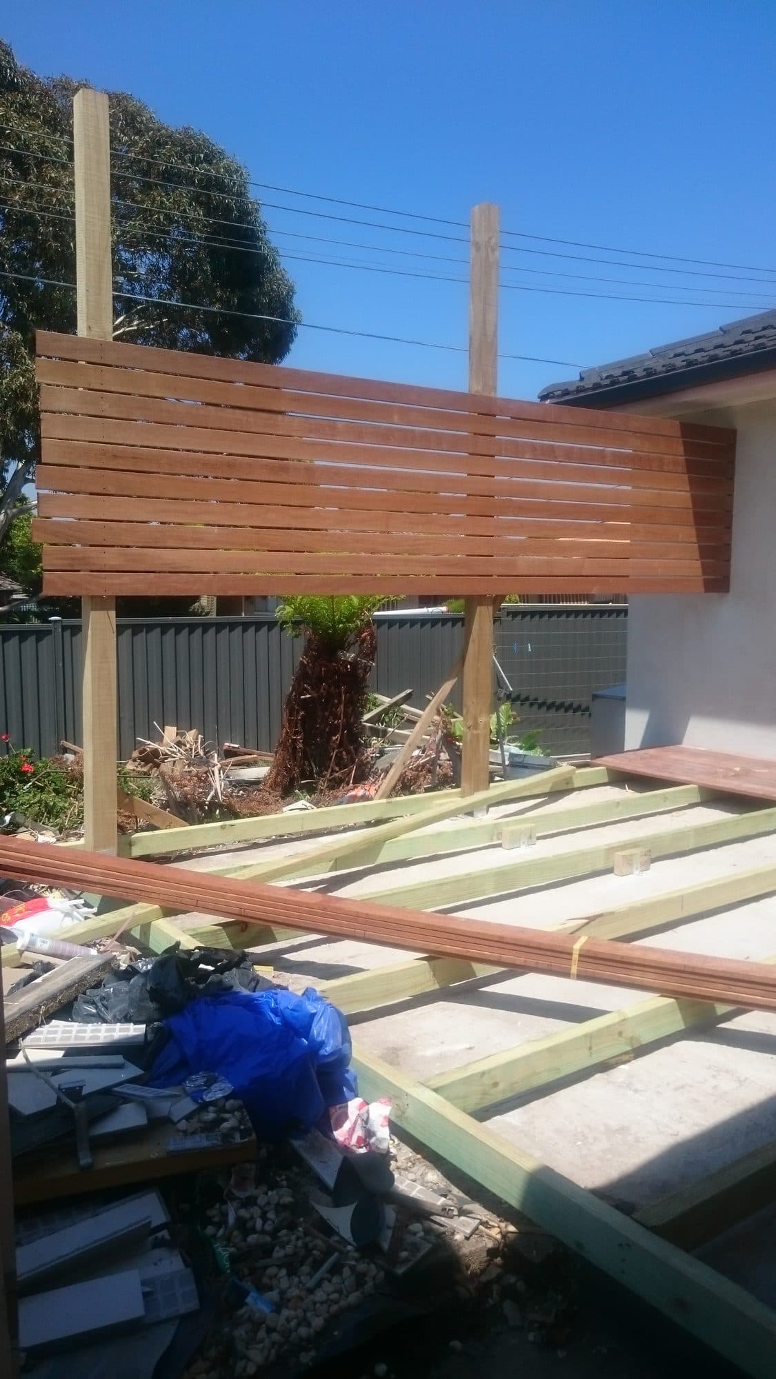 A horizontal timber slat screen fixed between two posts beside the deck frame
