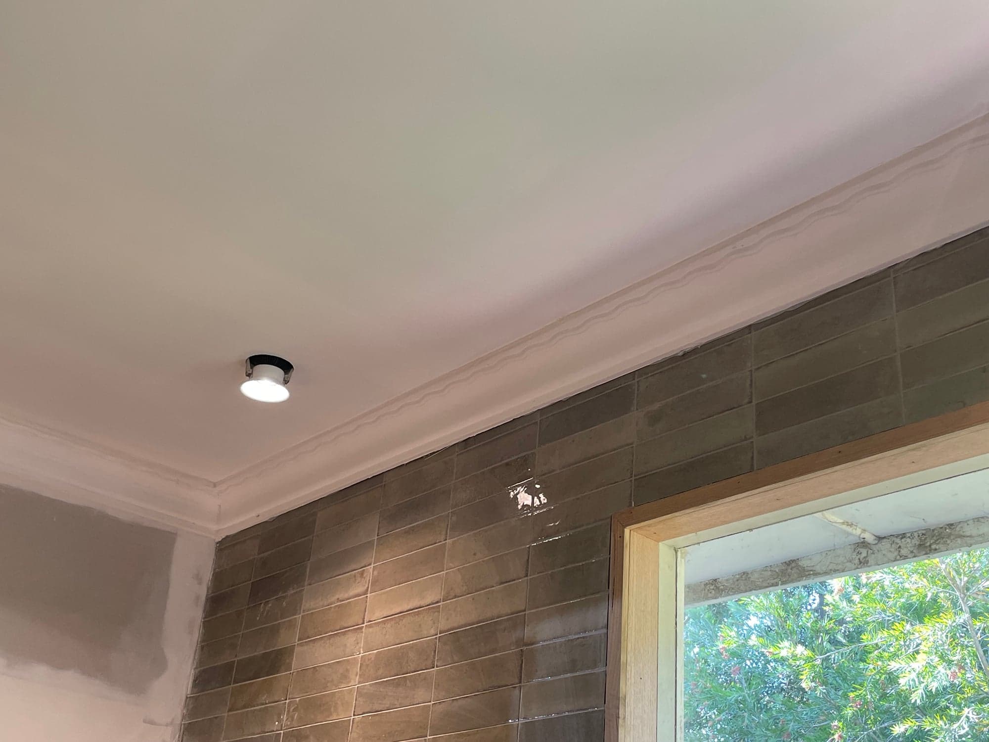 Tiling meeting the cornice under a raked ceiling, beside the window
