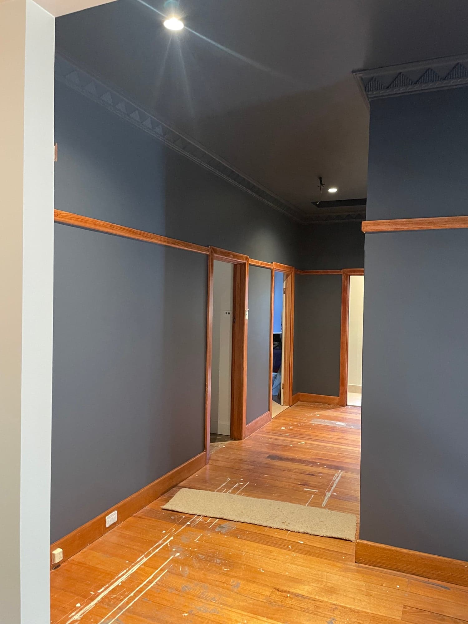 A hallway painted deep navy, with the original timber trims and a new timber floor